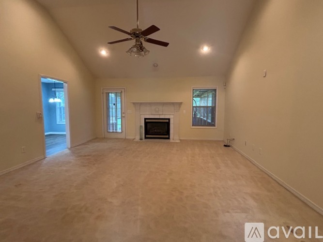 A spacious living room with a fireplace and a ceiling fan.