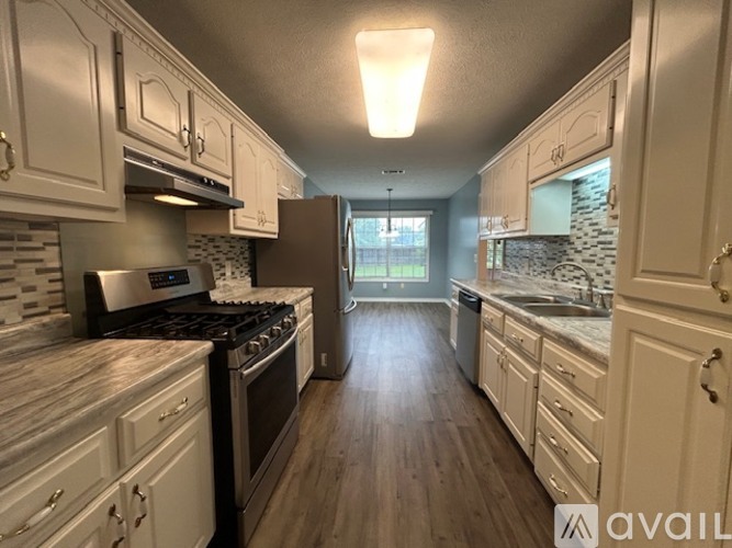 A kitchen with white cabinets and a wooden floor.