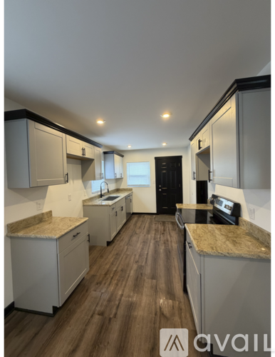 A kitchen with white cabinets and a wooden floor.