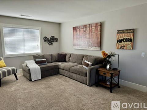 A living room with a grey sofa, a striped chair, and a painting on the wall.