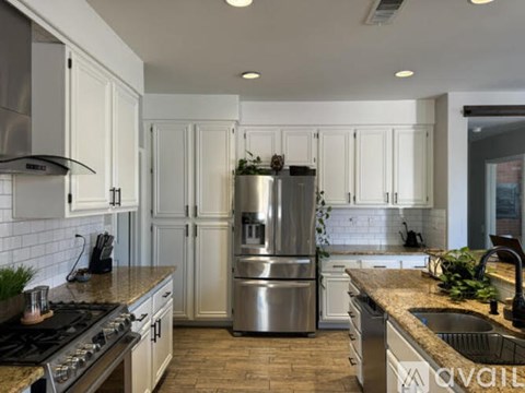 A modern kitchen with white cabinets and stainless steel appliances.