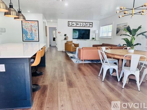 A living room with a wooden floor and a white table with chairs.