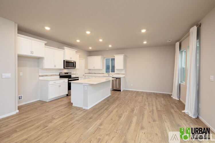 A spacious kitchen with white cabinets and a wooden floor.