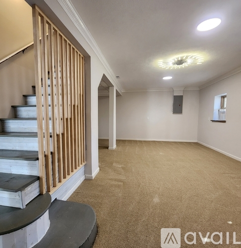 A spacious room with a staircase and a speaker on the wall.