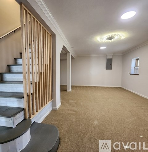 A spacious room with a staircase and a speaker on the wall.