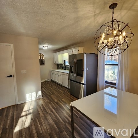A kitchen with a white counter top and wooden floors.