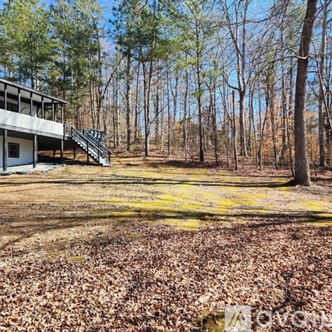 A house with a staircase is surrounded by trees.