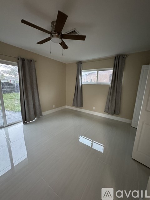 A room with a ceiling fan and sliding glass doors.