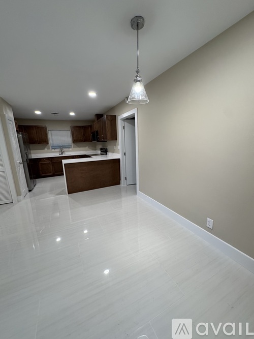 A kitchen with white flooring and a pendant light hanging from the ceiling.