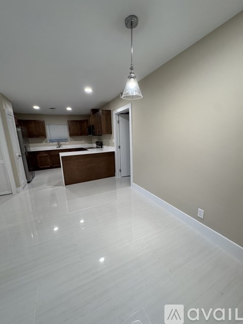 A kitchen with white flooring and a pendant light hanging from the ceiling.