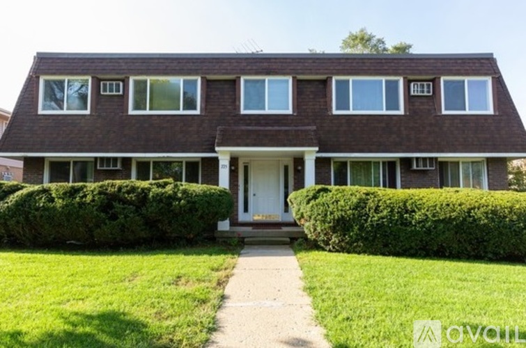 A house with a white door and windows is surrounded by green bushes.