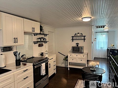 A kitchen with white cabinets and black countertops.