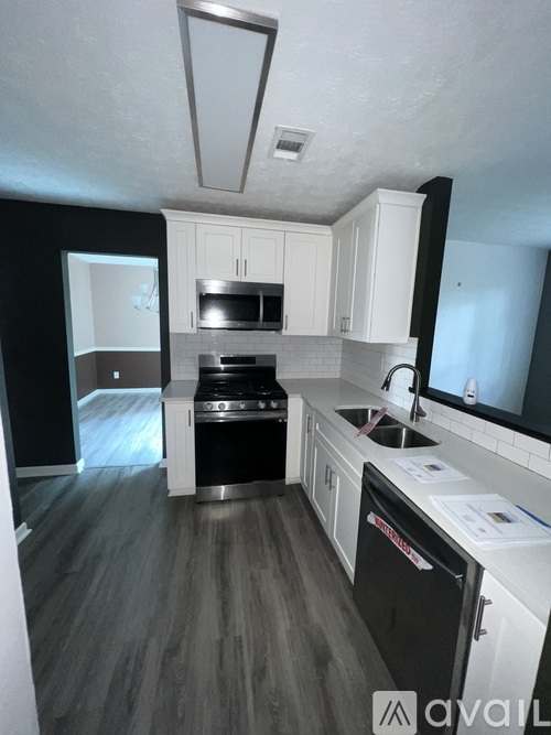 A kitchen with black appliances and white cabinets.
