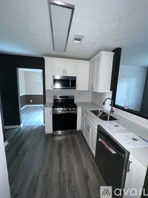 A kitchen with black appliances and white cabinets.