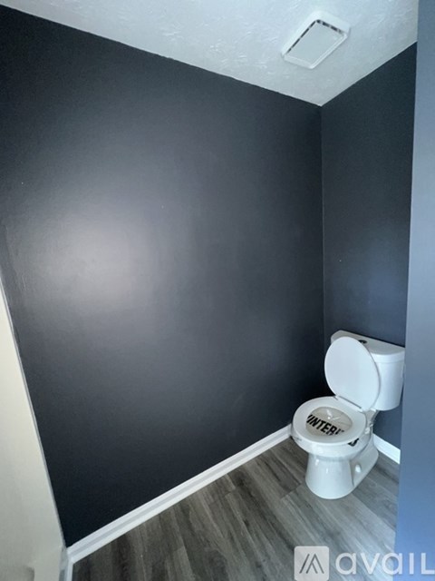 A white toilet with the word "WINTER" on the tank is in a bathroom with a dark grey wall.