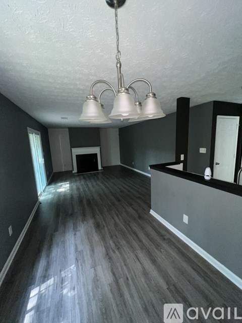 A room with wooden floors and a chandelier hanging from the ceiling.