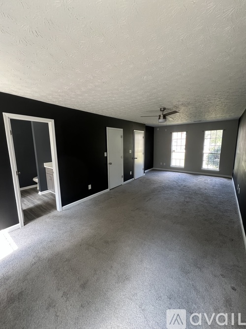 A spacious room with a ceiling fan and large windows.