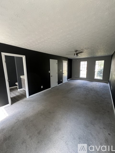 A spacious room with a ceiling fan and large windows.