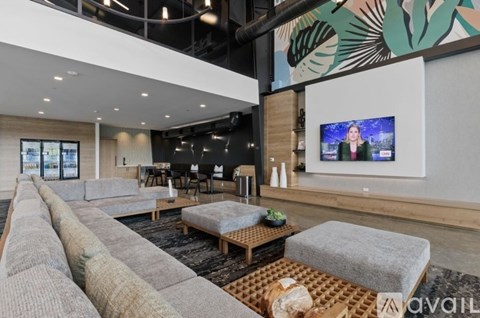 A modern living room with a long grey sofa and a television on the wall.