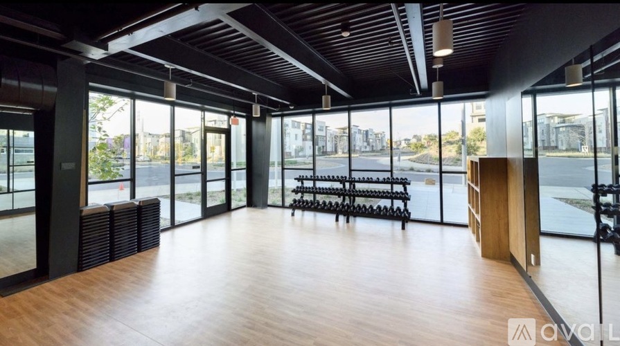 A spacious room with wooden floors and large windows overlooking a cityscape.
