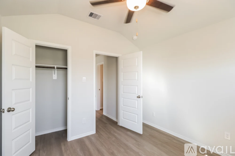 A room with a ceiling fan and three doors.