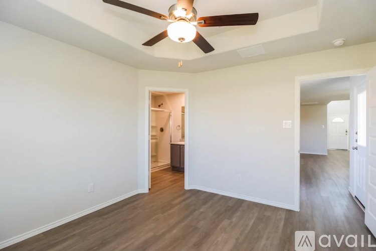 A room with a ceiling fan and wooden flooring.