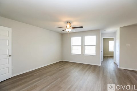 A spacious room with wooden flooring and a ceiling fan.
