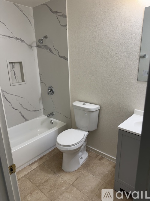 A white toilet sits in a bathroom next to a bathtub.