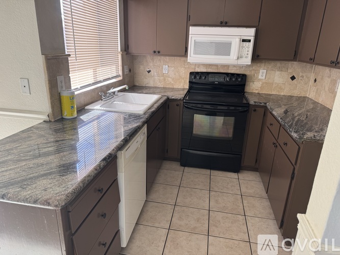 A kitchen with a black oven and a white microwave.