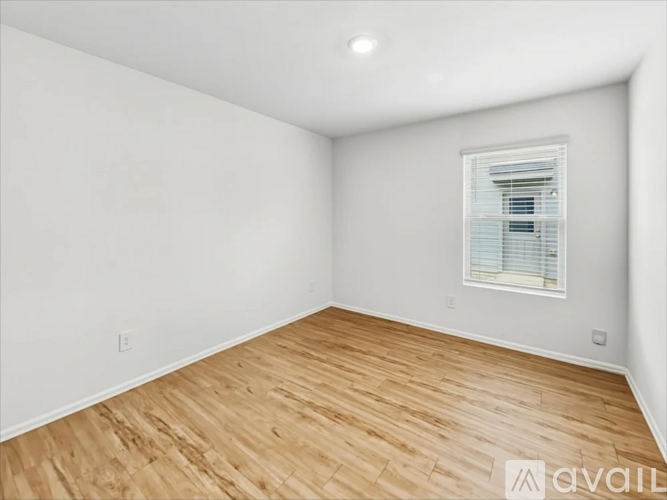 A room with wooden flooring and a window with blinds.