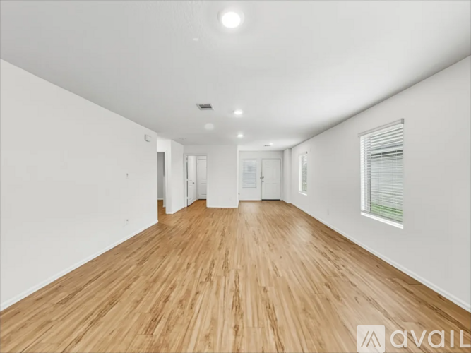 A spacious room with wooden flooring and white walls.
