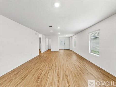 A spacious room with wooden flooring and white walls.
