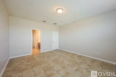 A spacious room with tiled flooring and white walls.
