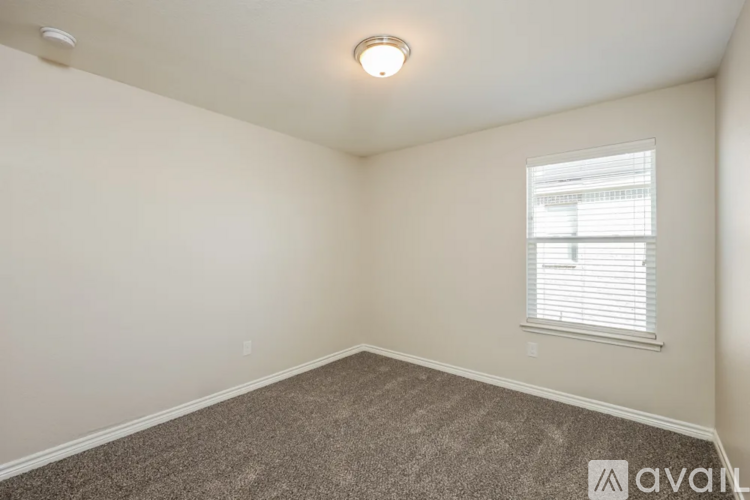 A room with a carpeted floor and a window with blinds.