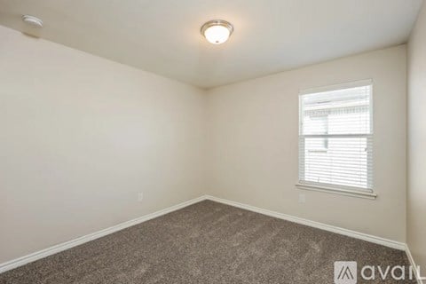 A room with a carpeted floor and a window with blinds.