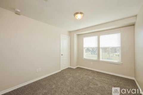 A room with a carpeted floor, a window with blinds, and a door.
