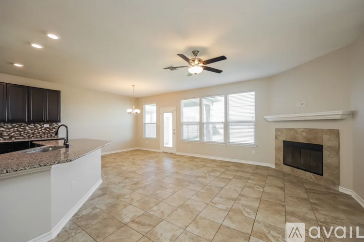 A spacious living room with a fireplace and a kitchen area with a sink.