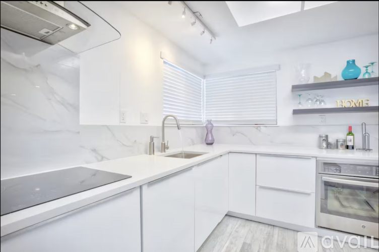 A modern kitchen with white cabinets and a stainless steel refrigerator.