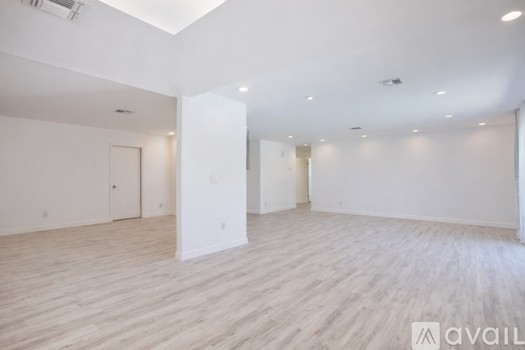 A spacious room with wooden flooring and white walls.