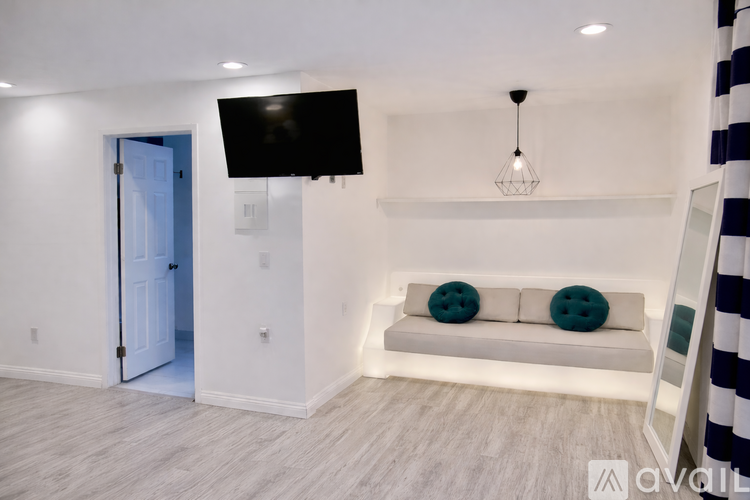 A living room with a white couch and a television mounted on the wall.
