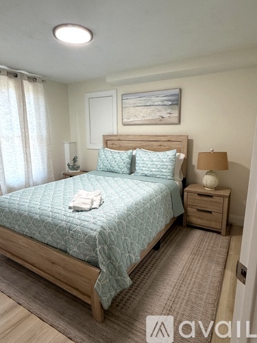 A bedroom with a bed, nightstands, and a painting on the wall.
