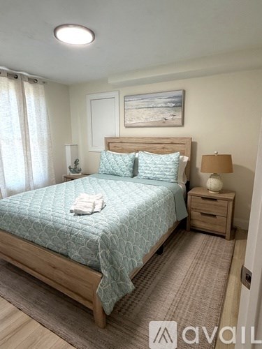 A bedroom with a bed, nightstands, and a painting on the wall.