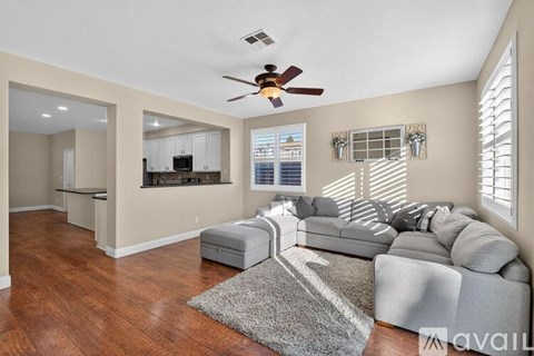 A living room with a grey couch and a ceiling fan.