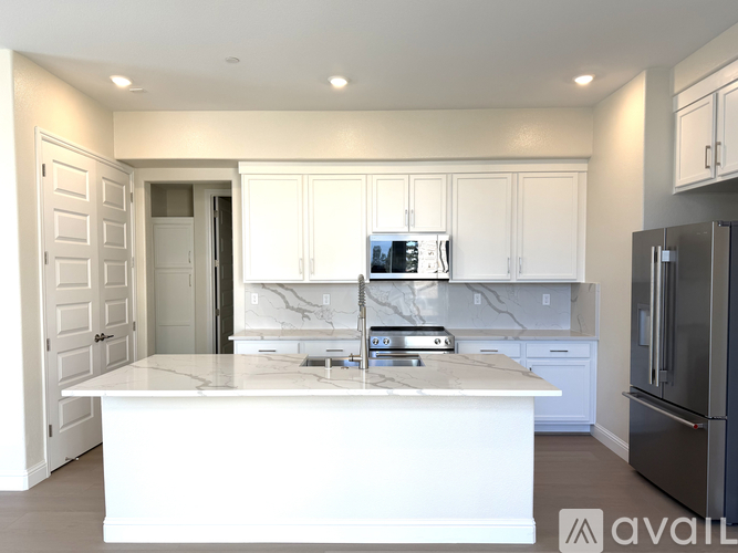 A modern kitchen with white cabinets and a marble backsplash.