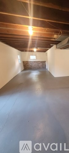 A spacious attic room with wooden beams on the ceiling.
