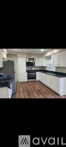 A kitchen with white cabinets and a black countertop.