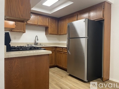 A kitchen with a stainless steel refrigerator and wooden cabinets.