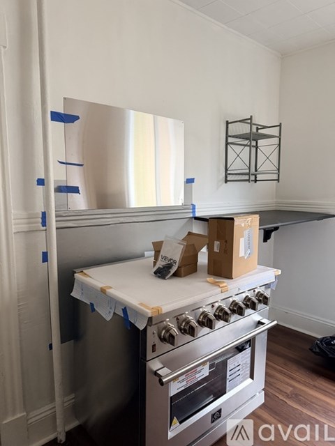 A kitchen under renovation with a stove and a box on the counter.