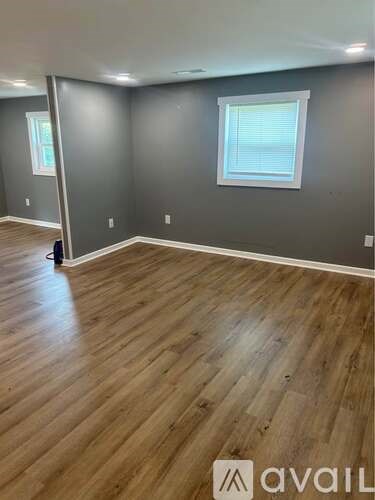 A room with wooden flooring and a window with blinds.