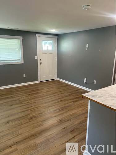 A room with a white door and wooden flooring.